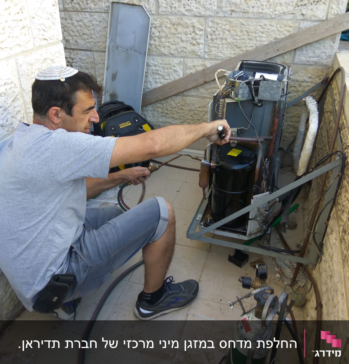 טכנאי מתקין מזגן עם כלים וצינורות